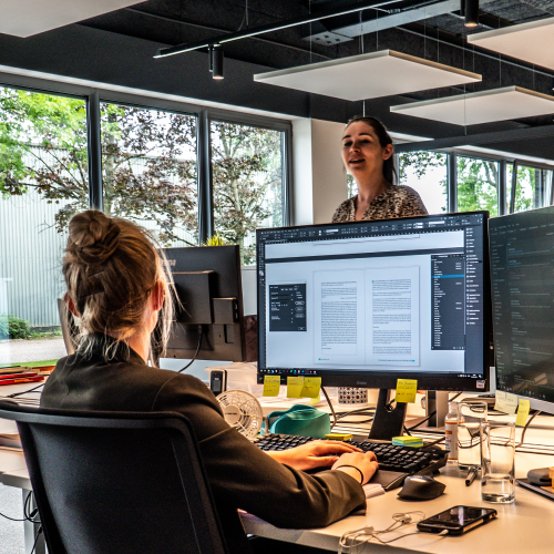 Crius employee sitting at desk talking to other employee